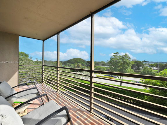 Outdoor balcony with chairs overlooking a highway and scenic greenery.
