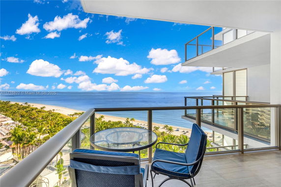 Balcony view overlooking the ocean and beach from a high-rise building.