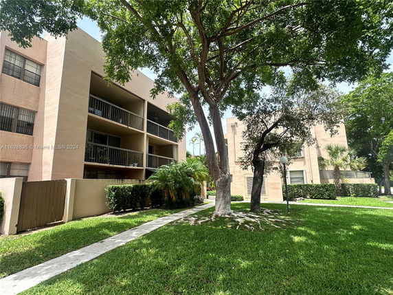 Front view of an apartment building with multiple balconies and a grassy area.