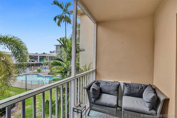 Balcony view overlooking a swimming pool and greenery.