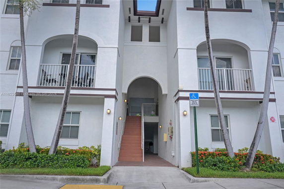 Front view of a multi-story building with arched balconies and an entryway.