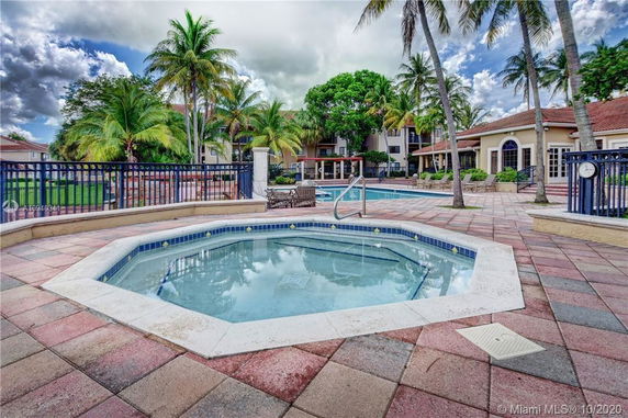 Outdoor swimming pool area with palm trees and a surrounding patio.