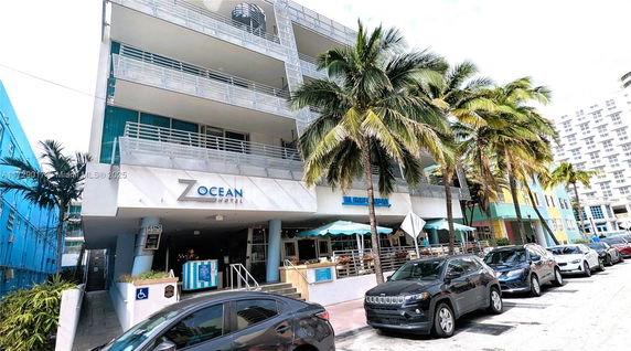 Front view of a multi-story hotel with balconies and palm trees.