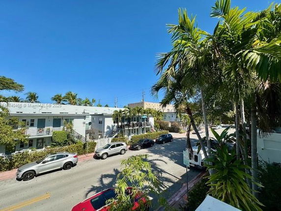 Street view with parked cars and surrounding buildings.
