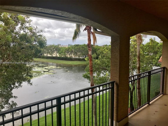View from a balcony overlooking a body of water surrounded by greenery.