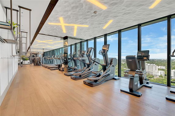 Interior view of a modern gym with exercise equipment and large windows.