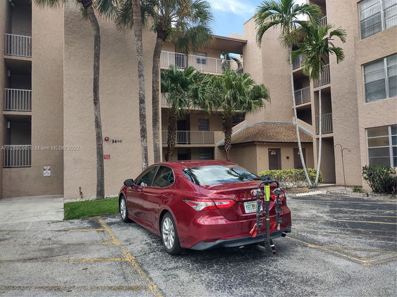 Outdoor parking area in front of a residential building with multiple floors.