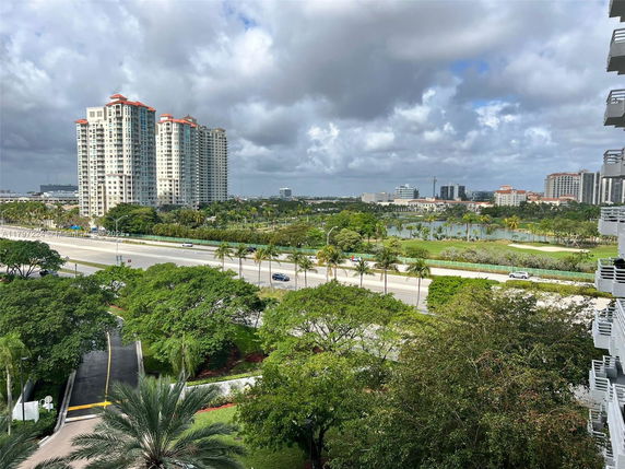 Elevated view of a cityscape with tall buildings and a road surrounded by lush greenery.