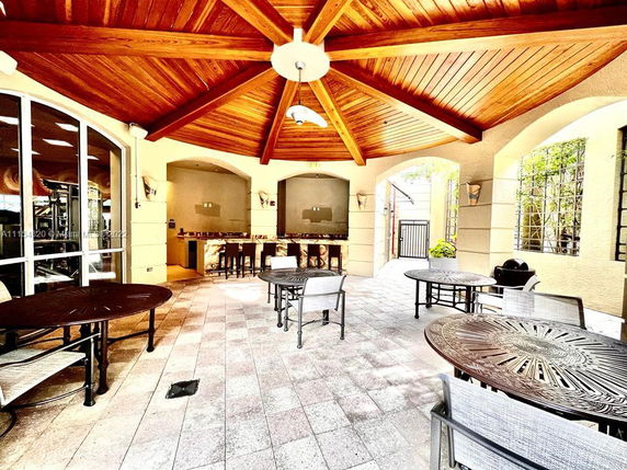 Indoor recreation area with tables and chairs under a wooden ceiling.