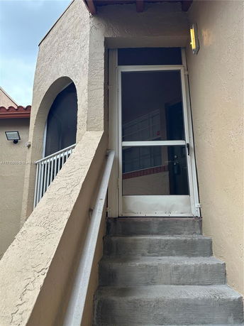 Front view of a building entrance with stairs and an arched design.