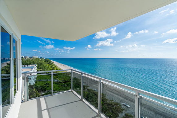 View from a balcony overlooking the ocean and beach.