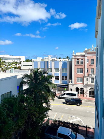 Street view with multiple buildings, cars, and palm trees