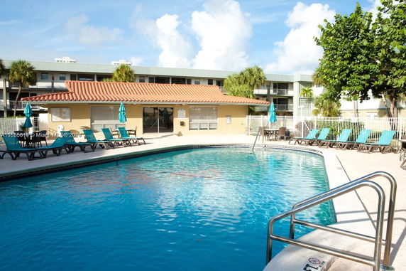 Outdoor swimming pool area with lounge chairs and shaded seating area.
