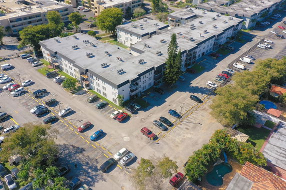 Aerial view of a residential building with an adjacent parking area.