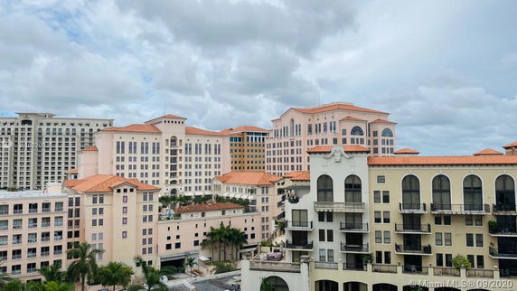 View of multiple residential and commercial buildings with Mediterranean-style architecture, featuring arched windows and red tile roofs.