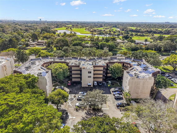 Aerial view of a multi-story residential building with a surrounding landscape of trees and green areas.