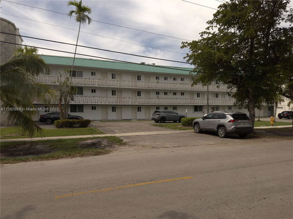 Front view of a three-story apartment building with a green roof and multiple balconies.