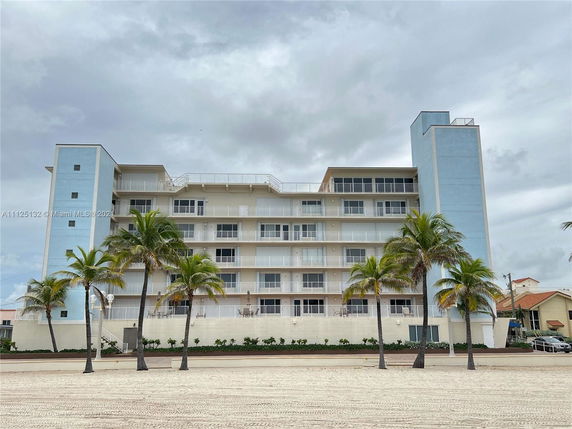 Front view of a multi-story beachside building with balconies.