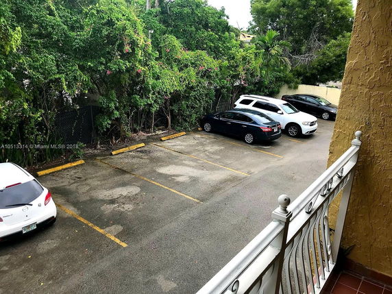 Parking area with multiple cars next to a building.