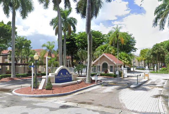 Front entrance of a condominium complex with gated entrance and sign.