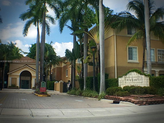 Front view of a multi-story building with palm trees and a sign reading 'Aventi.'