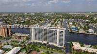 Aerial view of a multi-story building near a waterway with surrounding residential area.