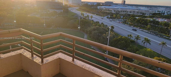 Panoramic view from a balcony showing a sports field and a cityscape in the distance.