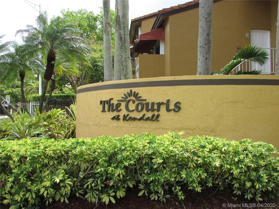 Front view of a building with yellow walls and a sign that reads 'The Courts at Kendall'.