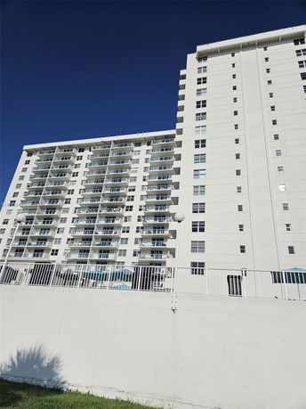 Front view of a tall apartment building with multiple balconies.