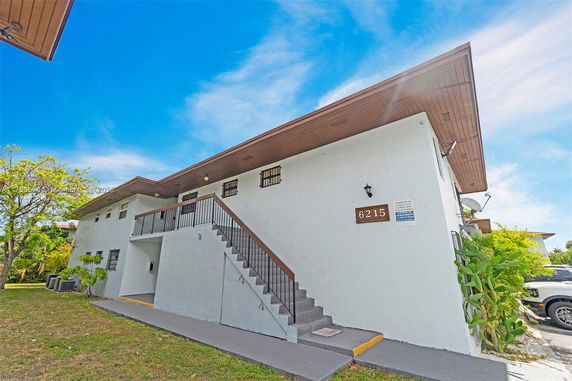 Front view of a two-story building with exterior stairs and number 6215 visible.
