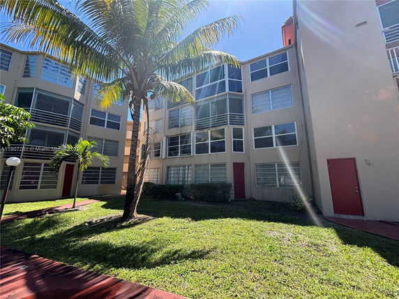 Front view of a multi-story residential building with large windows and red doors.