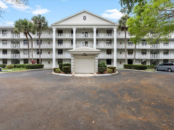 Front view of a multi-story residential building with balconies and columns.