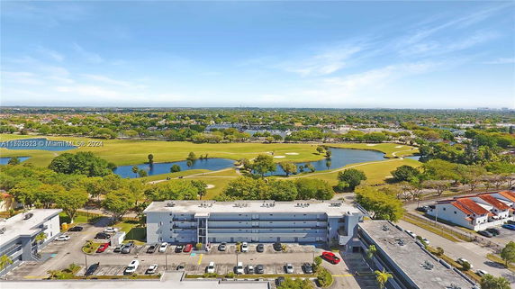Wide-angle view of buildings and surrounding green landscape with water features visible.