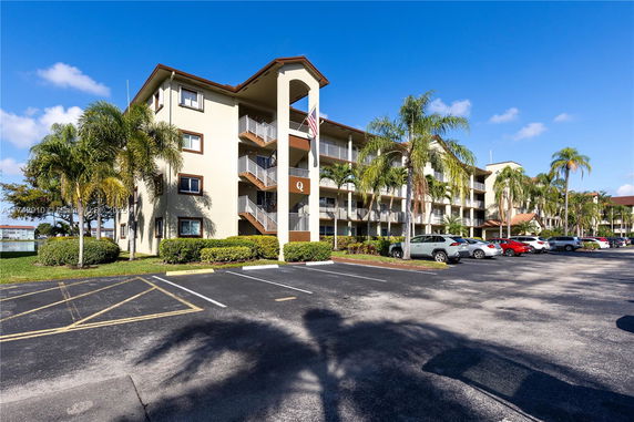 Front view of a multi-story residential building with balconies and parking area.