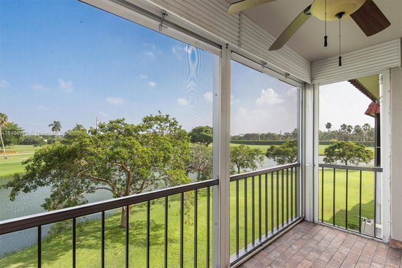 Balcony view of a landscaped area with trees and a pond.