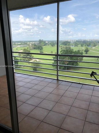 Panoramic view of a green landscape from a balcony with tiled flooring and railing.
