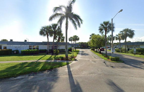 Front view of a single-story building with palm trees around.