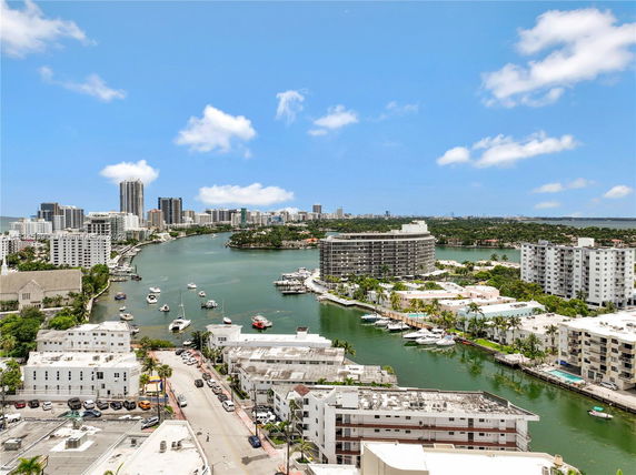 Panoramic view of a waterfront cityscape with high-rise buildings and boats in the water.