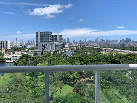Panoramic view of a city skyline with buildings and greenery.