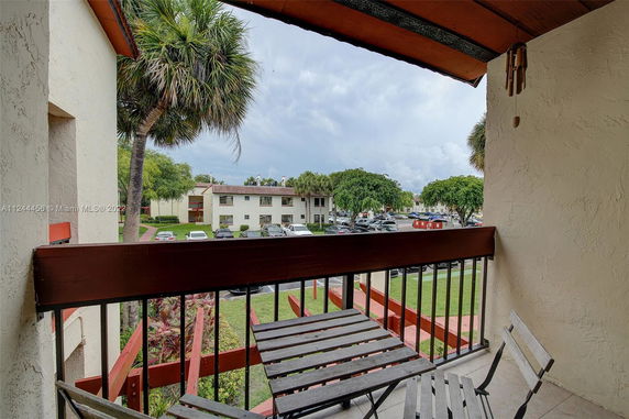 View from a balcony showing a residential area with parking and trees.