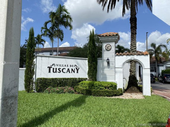 Front view of entrance to Villas de Tuscany with decorative arch and landscaped area.