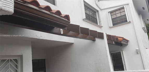Side view of a white building with windows and a brown tiled awning.