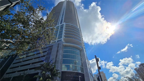 Front view of a tall modern skyscraper with rounded balconies and glass facade.