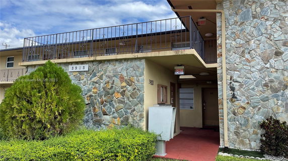 Front view of a two-story building with stone exterior and a balcony.
