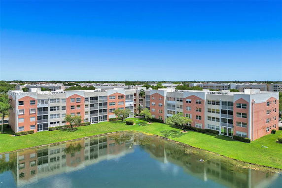 Front view of a multi-story apartment building with a water body in front.