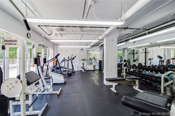 Indoor gym with various exercise equipment and mirrors.