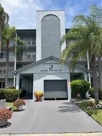 Front view of a multi-story building with balconies and a garage entrance.