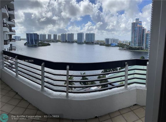 Panoramic view from a balcony overlooking water and distant buildings.