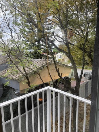View from a balcony overlooking a tiled roof and trees.