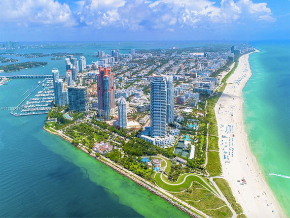 Aerial view of a coastal city with high-rise buildings, beaches, and marinas.